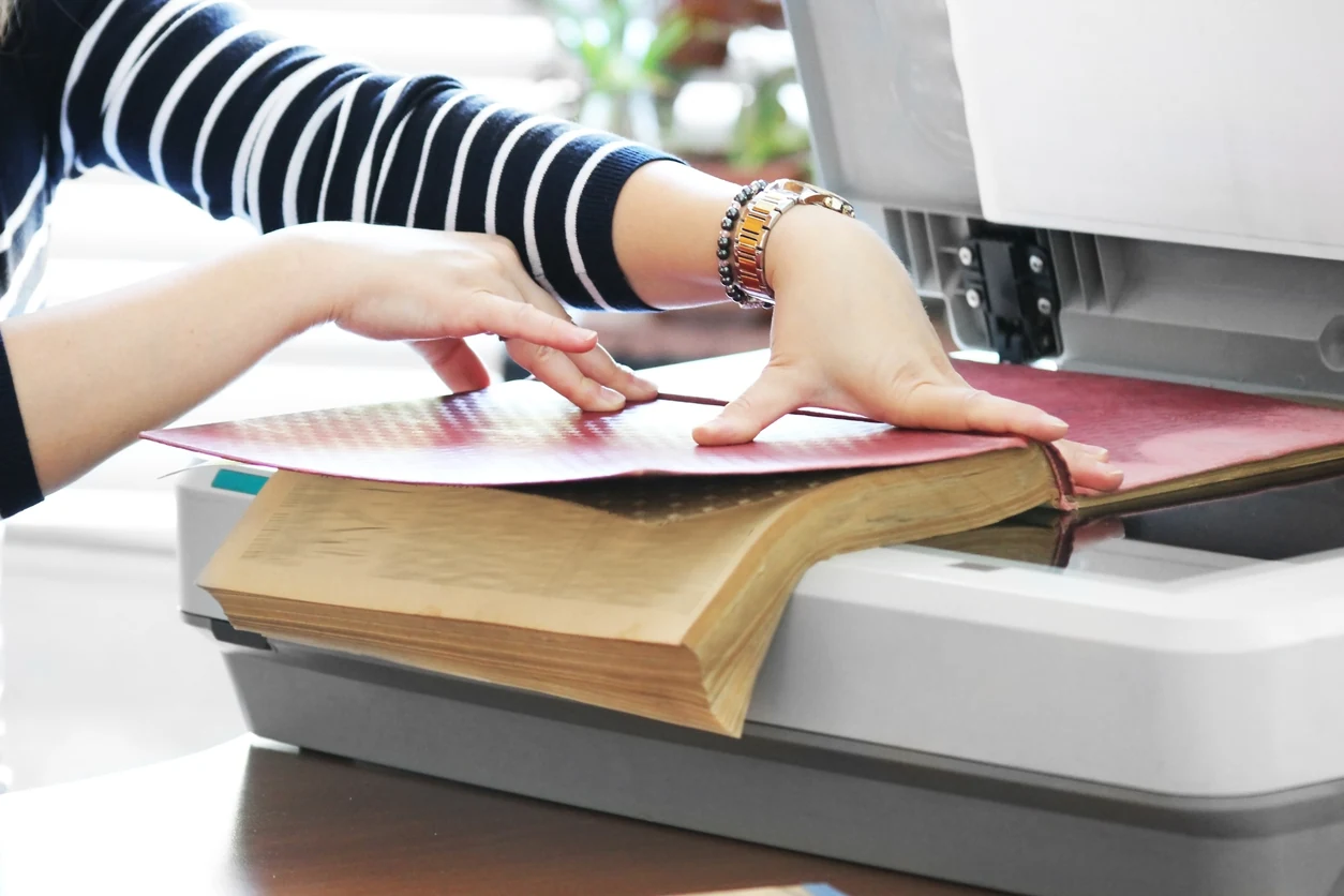 Gloved hands digitizing a book on a scanner