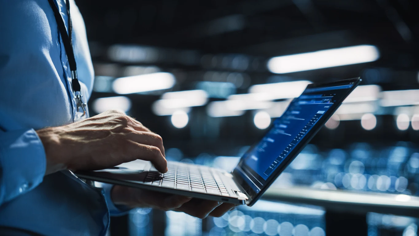 Specialist’s hands with a laptop between data center racks