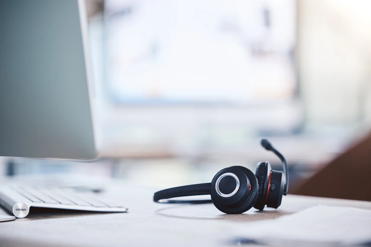 Technical support headset next to a keyboard, in front of the screen